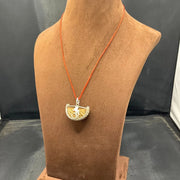 Close-up image of 1 Mukhi Rudraksha - One Face Kaju Rudraksha pendant with a lab certificate, highlighting its natural texture and shape.