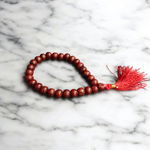 Close-up image of Lal Chandan Mala with natural red sandalwood beads in 108+1 and 27+1 variants, placed on a spiritual altar setting
