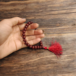Close-up image of Lal Chandan Mala with natural red sandalwood beads in 108+1 and 27+1 variants, placed on a spiritual altar setting