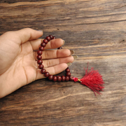 Close-up image of Lal Chandan Mala with natural red sandalwood beads in 108+1 and 27+1 variants, placed on a spiritual altar setting