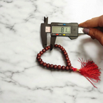 Close-up image of Lal Chandan Mala with natural red sandalwood beads in 108+1 and 27+1 variants, placed on a spiritual altar setting