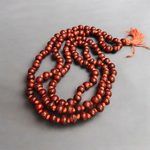 Close-up image of Lal Chandan Mala with natural red sandalwood beads in 108+1 and 27+1 variants, placed on a spiritual altar setting