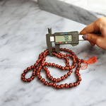 Close-up image of Lal Chandan Mala with natural red sandalwood beads in 108+1 and 27+1 variants, placed on a spiritual altar setting