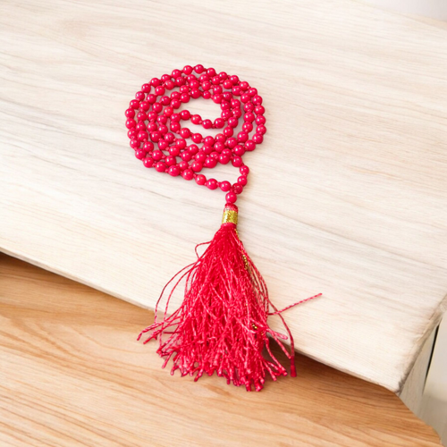 Close-up image of a Red Coral Mala with 4mm beads, showcasing the vibrant red color and traditional guru bead on a spiritual cloth