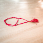 Close-up image of a Red Coral Mala with 4mm beads, showcasing the vibrant red color and traditional guru bead on a spiritual cloth