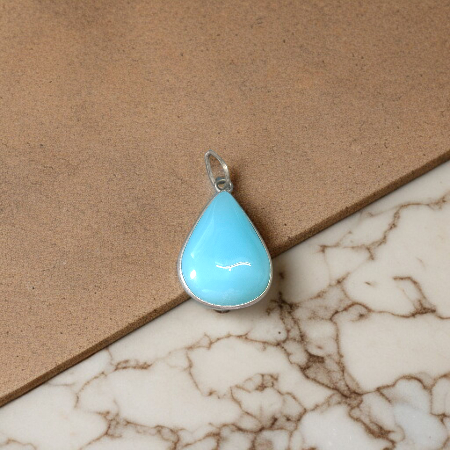 Close-up image of a natural Turquoise (Firoza) gemstone pendant with polished surface, paired with a black adjustable thread, displayed on a wooden background