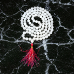 Close-up image of a premium 108+1 bead Sphatik (Crystal) Mala with 8MM beads, hand-knotted, radiant clear quartz beads, laid out on a white background
