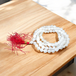 Close-up image of a premium 108+1 bead Sphatik (Crystal) Mala with 8MM beads, hand-knotted, radiant clear quartz beads, laid out on a white background