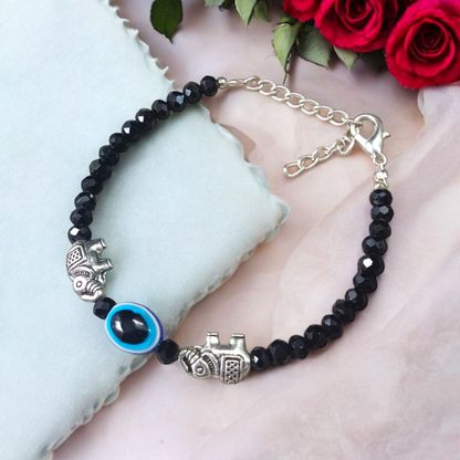 Close-up image of a stylish black bead anklet with a central evil eye charm, designed for girls by MALAWALA