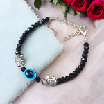 Close-up image of a stylish black bead anklet with a central evil eye charm, designed for girls by MALAWALA