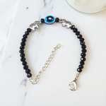 Close-up image of a stylish black bead anklet with a central evil eye charm, designed for girls by MALAWALA