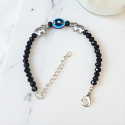 Close-up image of a stylish black bead anklet with a central evil eye charm, designed for girls by MALAWALA