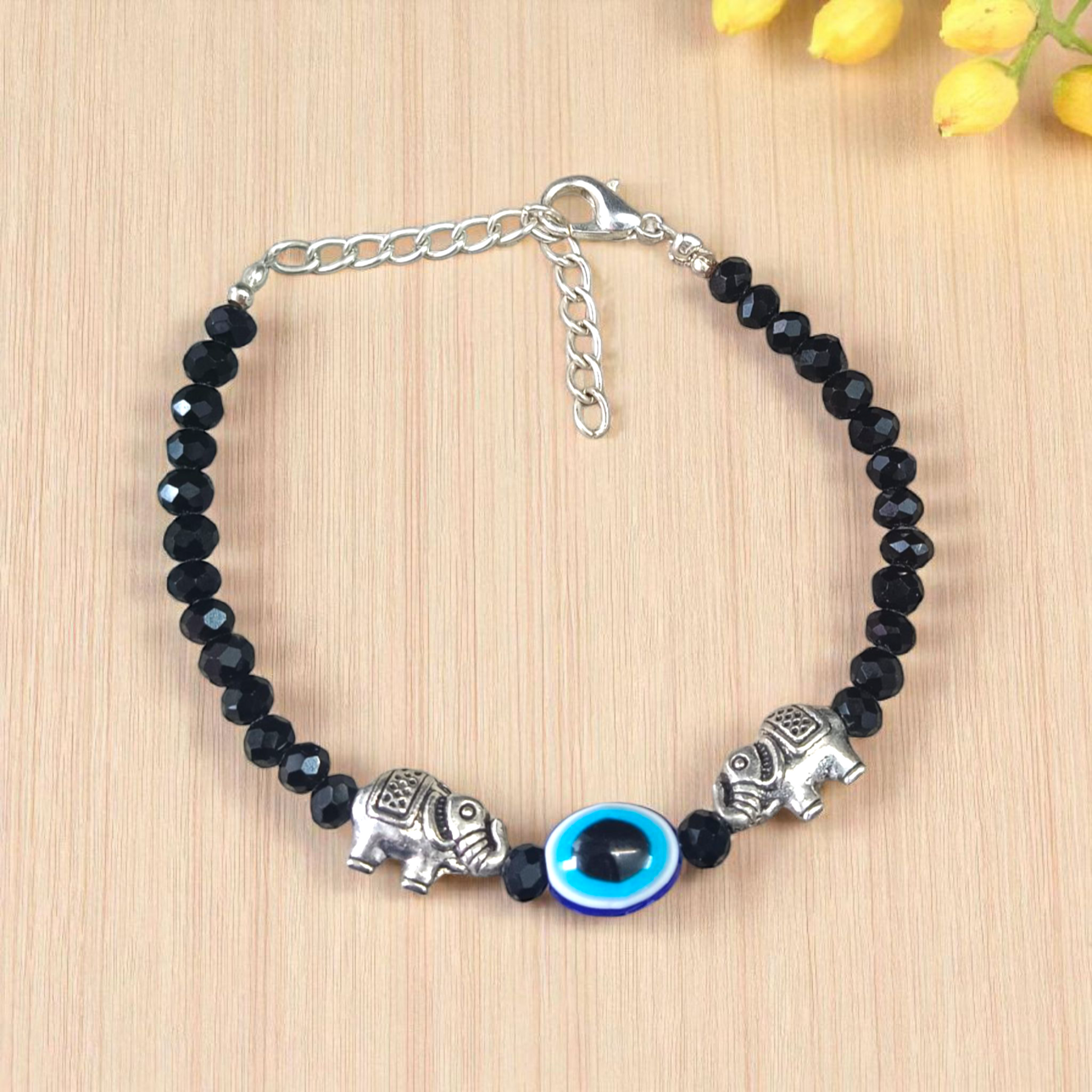 Close-up image of a stylish black bead anklet with a central evil eye charm, designed for girls by MALAWALA
