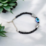 Close-up image of a stylish black bead anklet with a central evil eye charm, designed for girls by MALAWALA