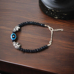 Close-up image of a stylish black bead anklet with a central evil eye charm, designed for girls by MALAWALA