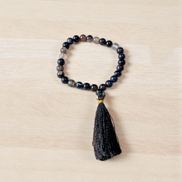 Close-up of Natural Sulemani Hakik Mala with 27+1 round 8mm black agate beads, arranged in a wrist-sized loop on a white background