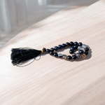 Close-up of Natural Sulemani Hakik Mala with 27+1 round 8mm black agate beads, arranged in a wrist-sized loop on a white background