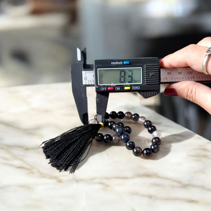 Close-up of Natural Sulemani Hakik Mala with 27+1 round 8mm black agate beads, arranged in a wrist-sized loop on a white background