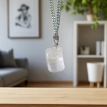 Close-up of a rough raw crystal quartz pendant with stainless steel chain, showcasing natural stone texture and clarity