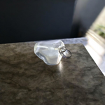 Close-up of a rough raw crystal quartz pendant with stainless steel chain, showcasing natural stone texture and clarity