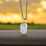 Close-up of a rough raw crystal quartz pendant with stainless steel chain, showcasing natural stone texture and clarity
