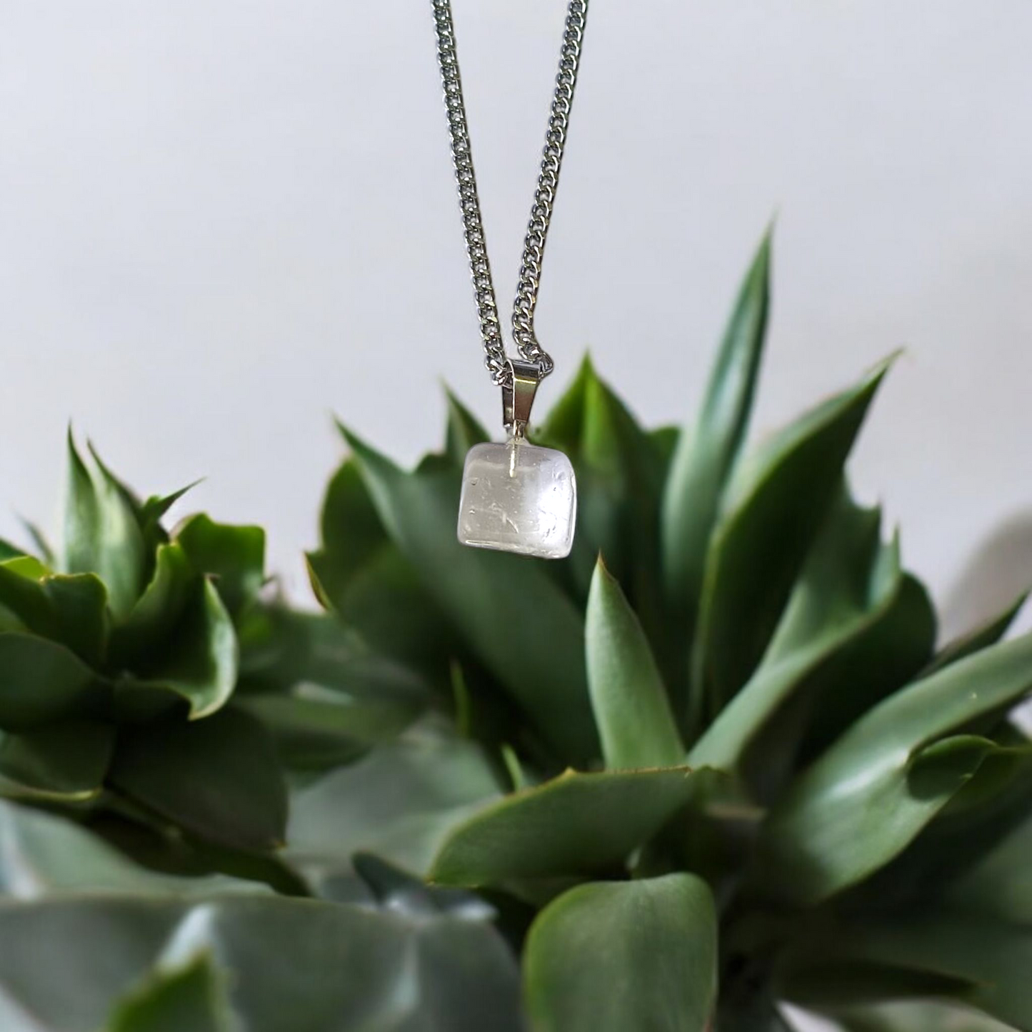 Close-up of a rough raw crystal quartz pendant with stainless steel chain, showcasing natural stone texture and clarity