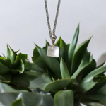 Close-up of a rough raw crystal quartz pendant with stainless steel chain, showcasing natural stone texture and clarity
