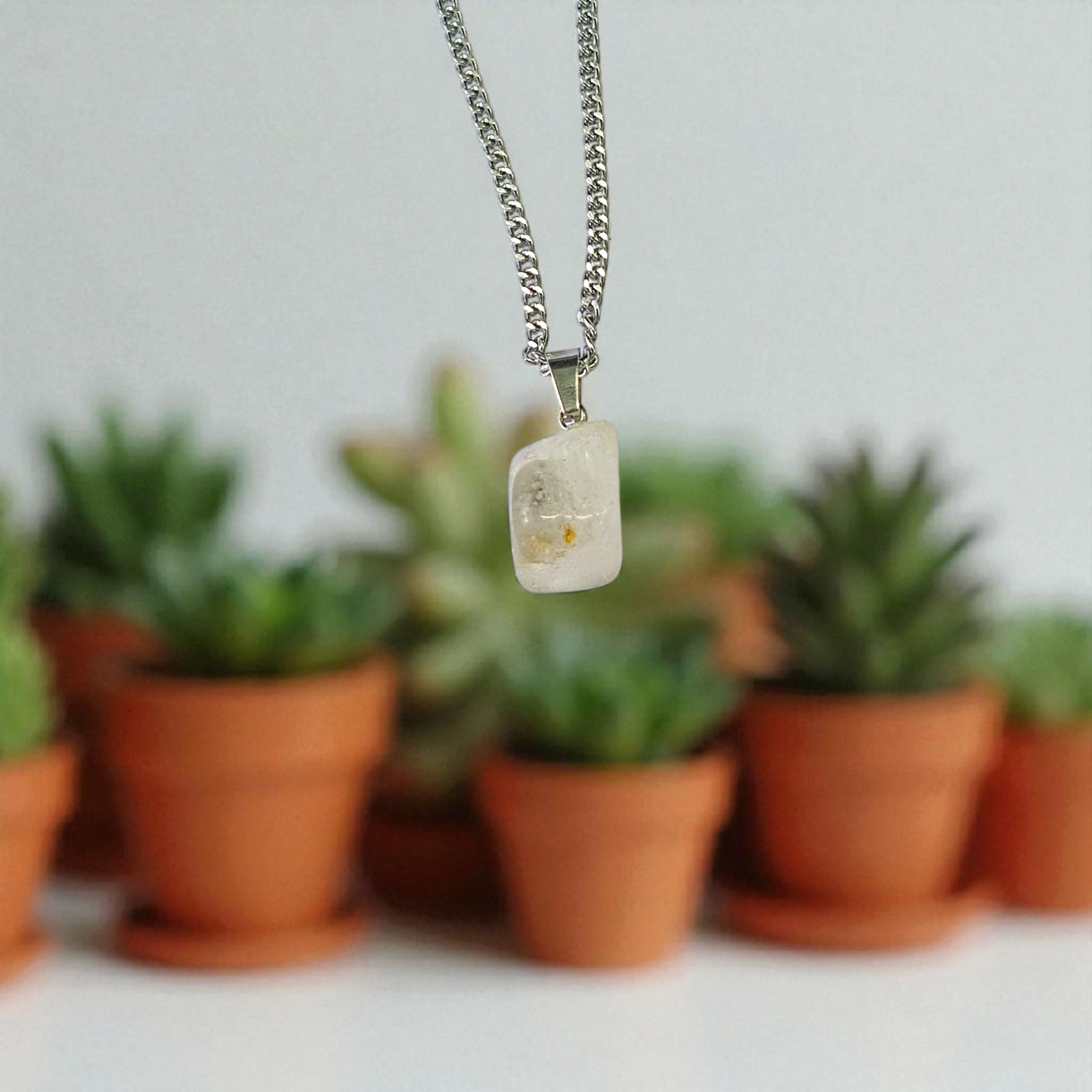 Close-up of a rough raw crystal quartz pendant with stainless steel chain, showcasing natural stone texture and clarity