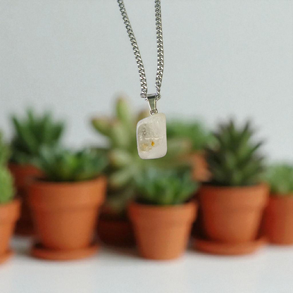 Close-up of a rough raw crystal quartz pendant with stainless steel chain, showcasing natural stone texture and clarity