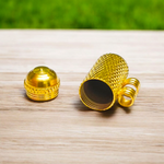 Five golden metal cylindrical taweez neatly arranged with Bhojpatra sheets on a clean white surface