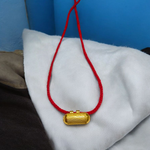 Five golden metal cylindrical taweez neatly arranged with Bhojpatra sheets on a clean white surface