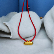 Five golden metal cylindrical taweez neatly arranged with Bhojpatra sheets on a clean white surface