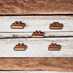 Five handcrafted cylindrical copper taweez placed beside Bhojpatra sheets on a clean, white background