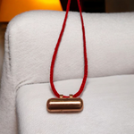 Five handcrafted cylindrical copper taweez placed beside Bhojpatra sheets on a clean, white background