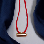Five handcrafted cylindrical copper taweez placed beside Bhojpatra sheets on a clean, white background