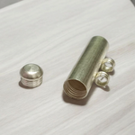 Five silver-plated cylindrical taweez amulets with accompanying Bhojpatra sheets placed neatly on a white surface