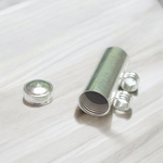 Five silver-plated cylindrical taweez amulets with accompanying Bhojpatra sheets placed neatly on a white surface