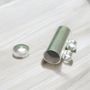 Five silver-plated cylindrical taweez amulets with accompanying Bhojpatra sheets placed neatly on a white surface