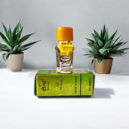 Glass bottle of 2ML Chameli Attar by Veena, adorned with a golden cap and floral-themed label, surrounded by jasmine flowers on a wooden surface