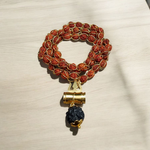 Gold-wired Rudraksha mala with 8mm beads, featuring a silver-tone Trishul pendant, arranged neatly on a dark wooden background