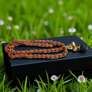 Gold-wired Rudraksha mala with 8mm beads, featuring a silver-tone Trishul pendant, arranged neatly on a dark wooden background
