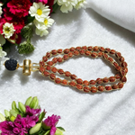 Gold-wired Rudraksha mala with 8mm beads, featuring a silver-tone Trishul pendant, arranged neatly on a dark wooden background