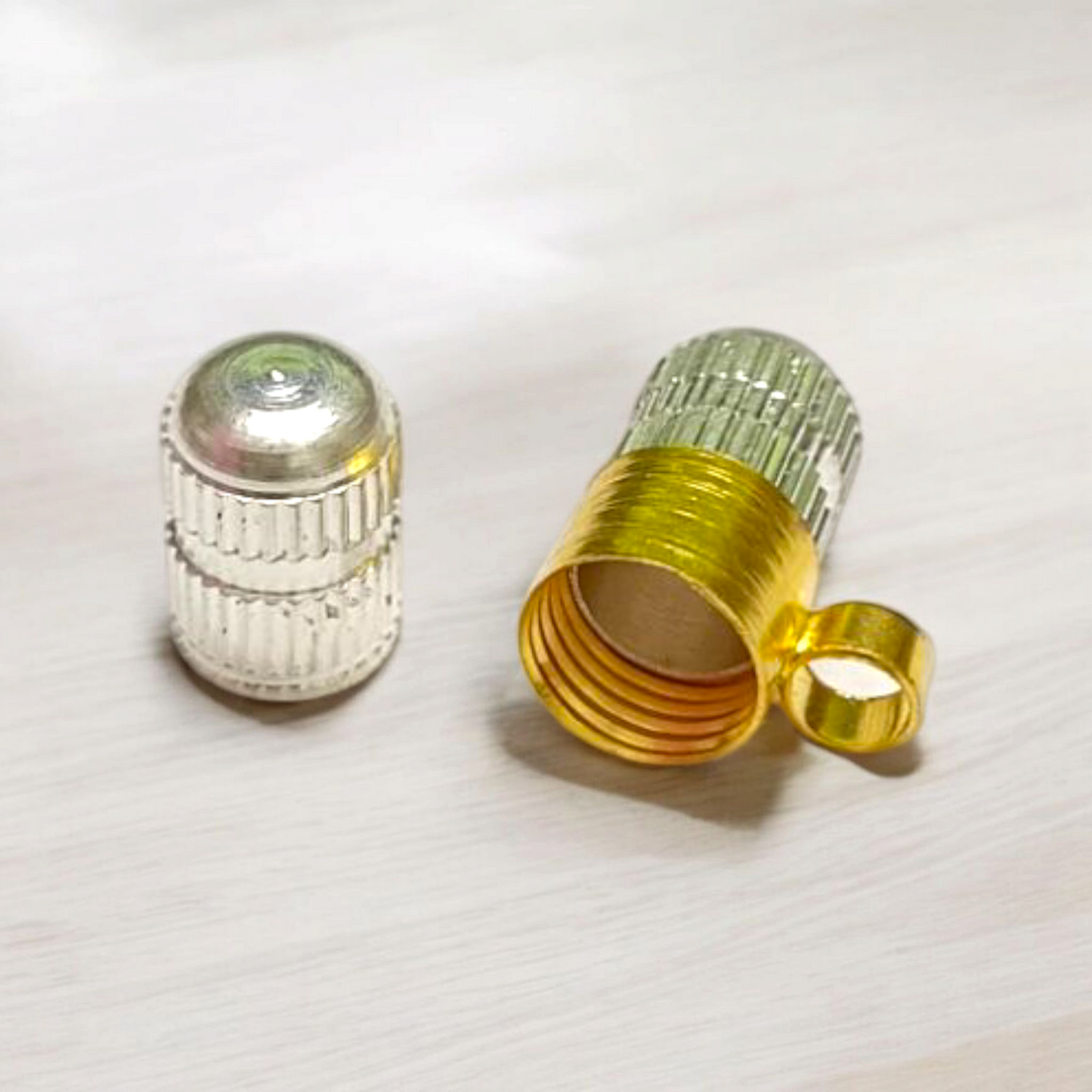 Golden and silver taweez set displayed with a Bhojpatra sheet on a wooden background
