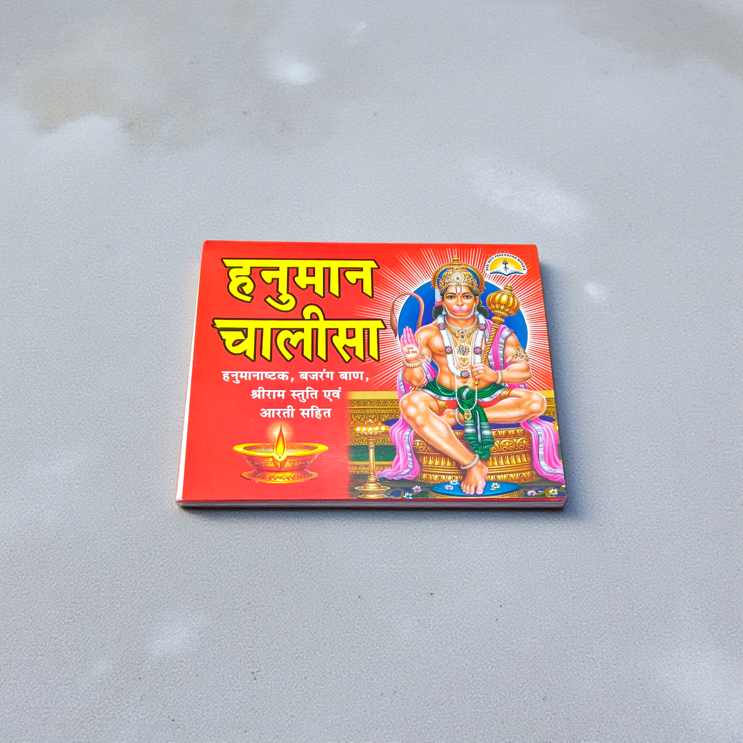 Hanuman Chalisa Hindi Book with colourful pages and devotional cover art placed near diya and flowers