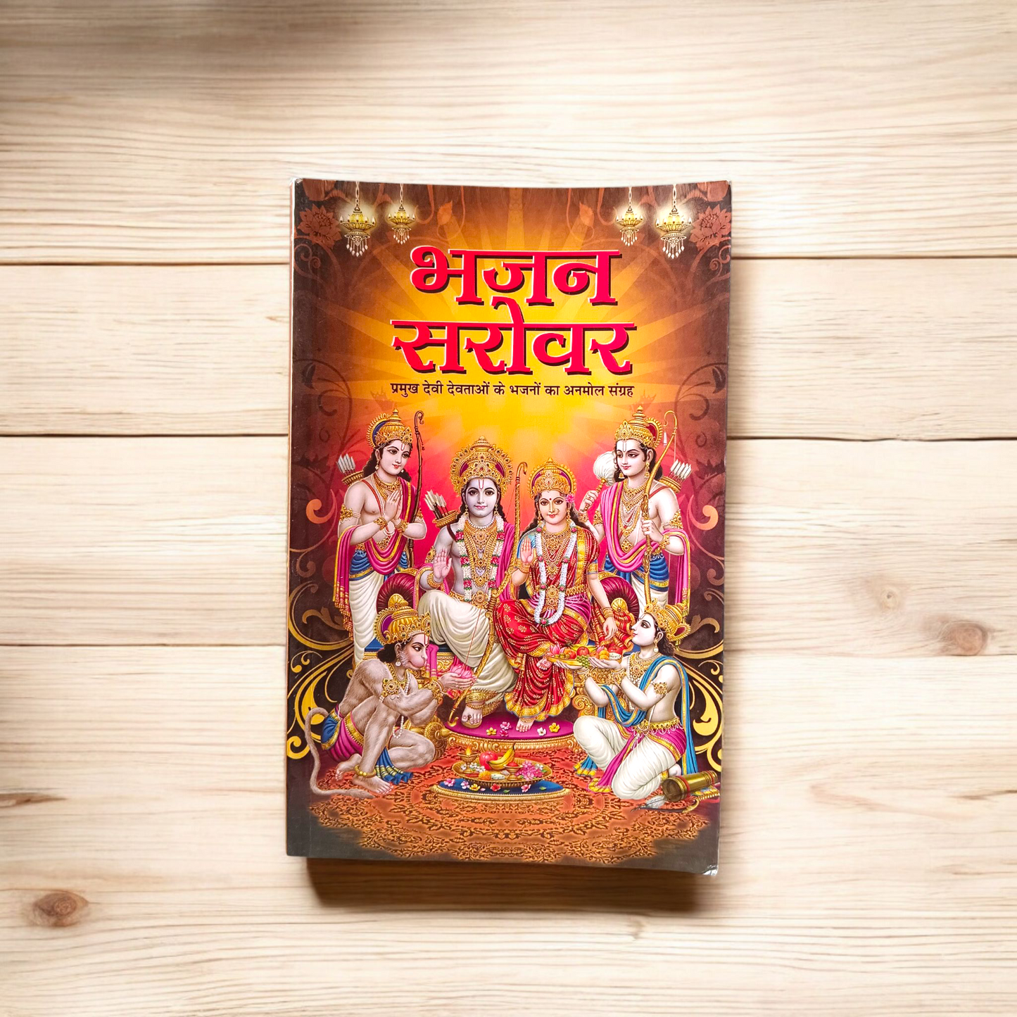 Image of Bhajan Sarover Book in Hindi with vibrant cover and devotional design placed on a wooden prayer table