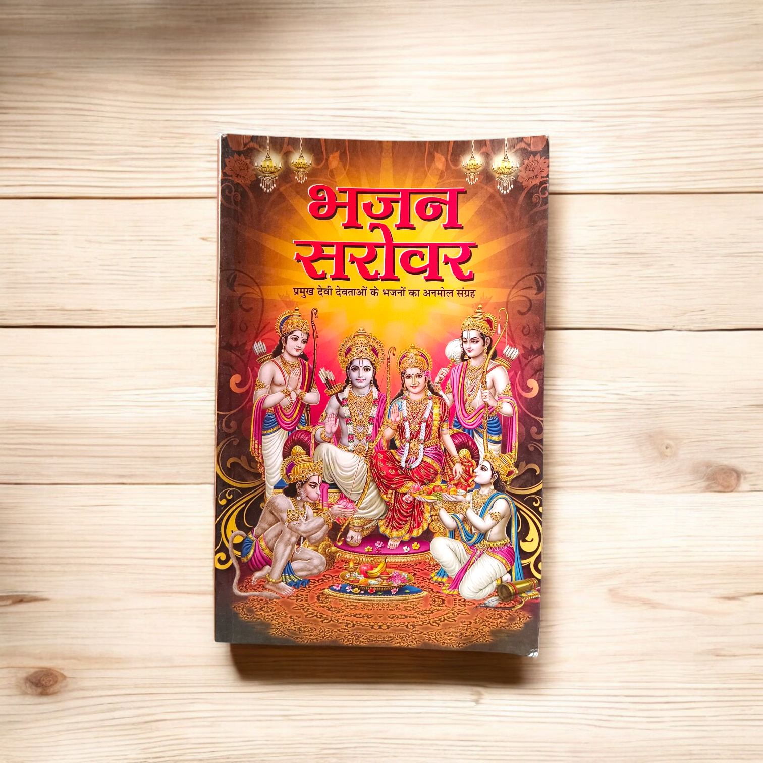 Image of Bhajan Sarover Book in Hindi with vibrant cover and devotional design placed on a wooden prayer table