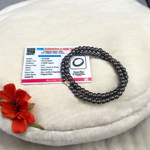 Image of Magnetic Mala made of black hematite beads, laid out in a spiral on a white background