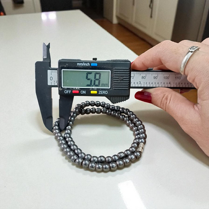 Image of Magnetic Mala made of black hematite beads, laid out in a spiral on a white background