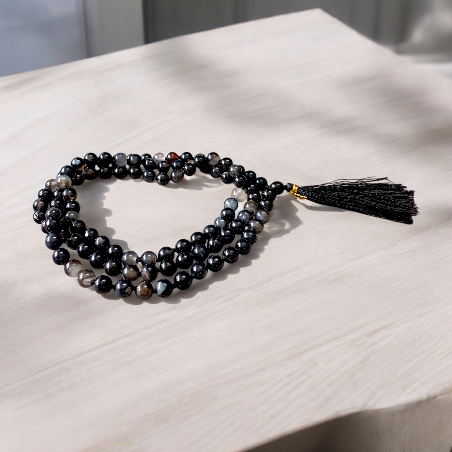 Image of Natural Sulemani Hakik (Black Agate) Mala with 108+1 and 27+1 polished 8mm round beads, displayed on a white background
