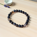 Image of Natural Sulemani Hakik Bracelet with 8mm round black agate beads in a stretchable design, displayed in a circular shape on a white surface